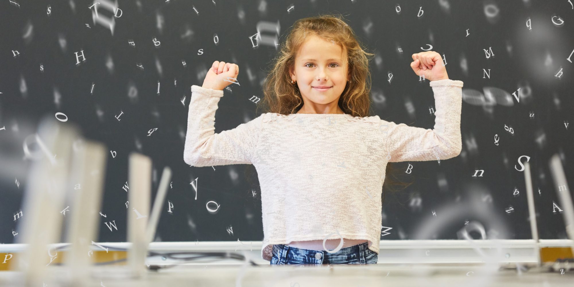 Girl in elementary school in front of blackboard with letters